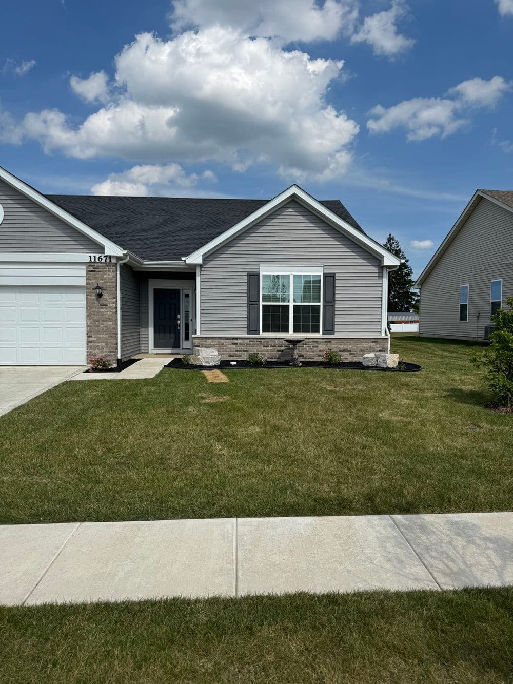 Modern single-family home with gray siding, stone accents, and a well-kept lawn.