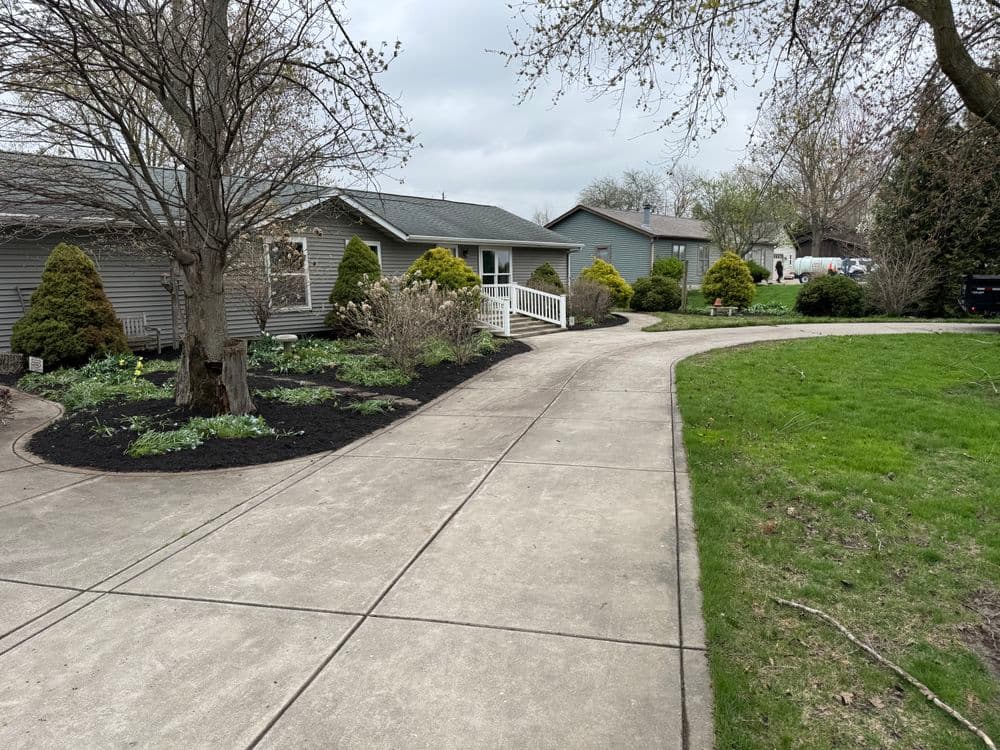 Residential landscaping with a curved driveway, flower beds, and well-maintained greenery.