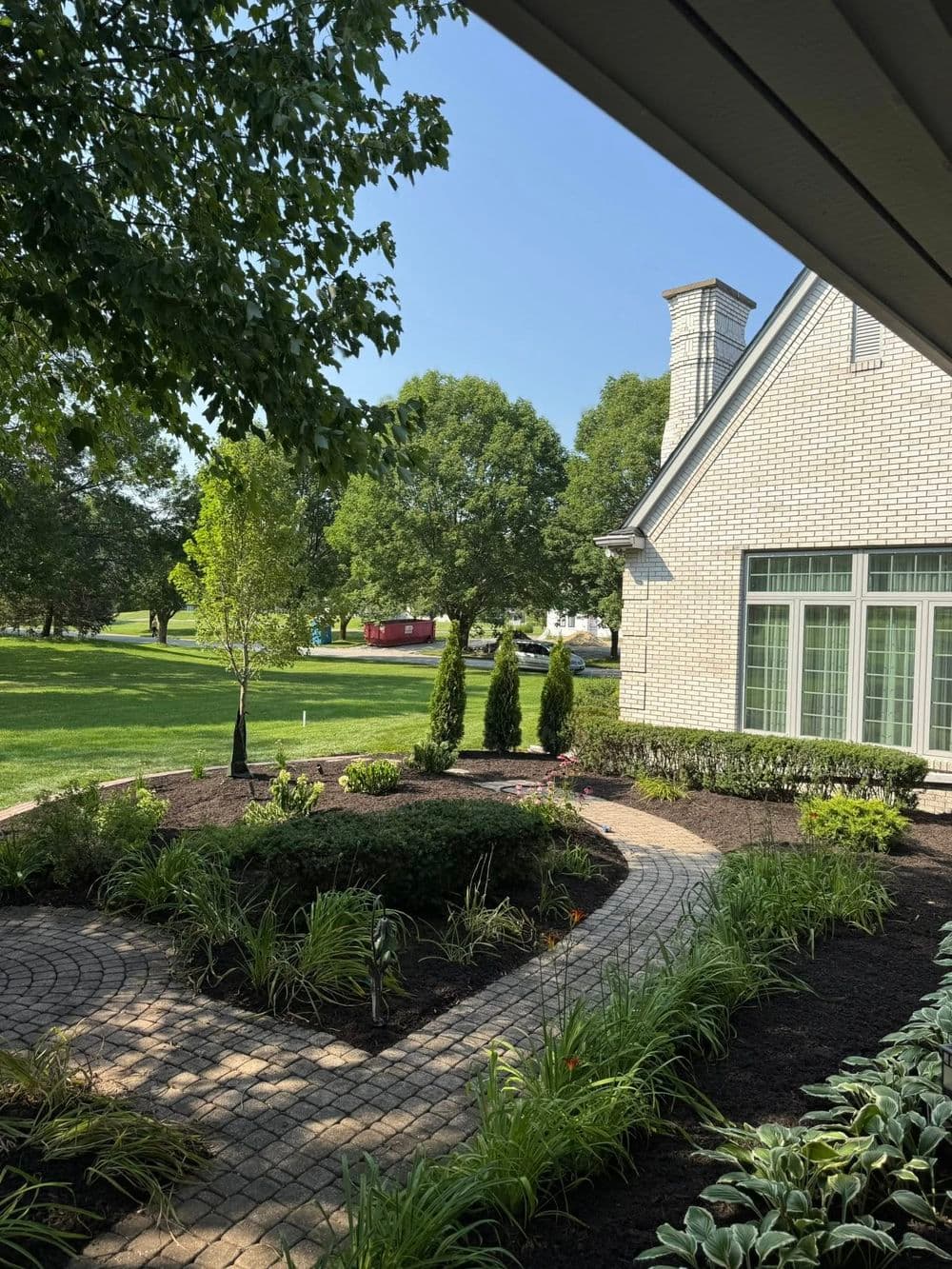 Lush landscaped garden with a curved stone pathway and modern home exterior on a sunny day.